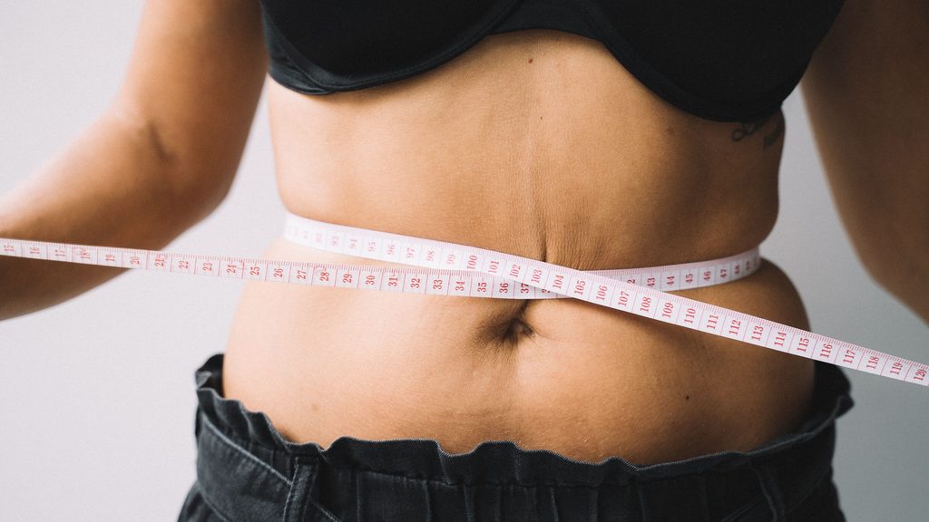 woman losing weight measuring her waist